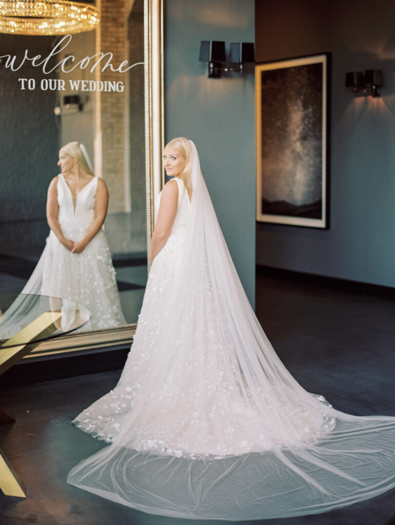 Bride is getting ready in front of a mirror in wedding dress and veil at the Standard Chicago wedding venue