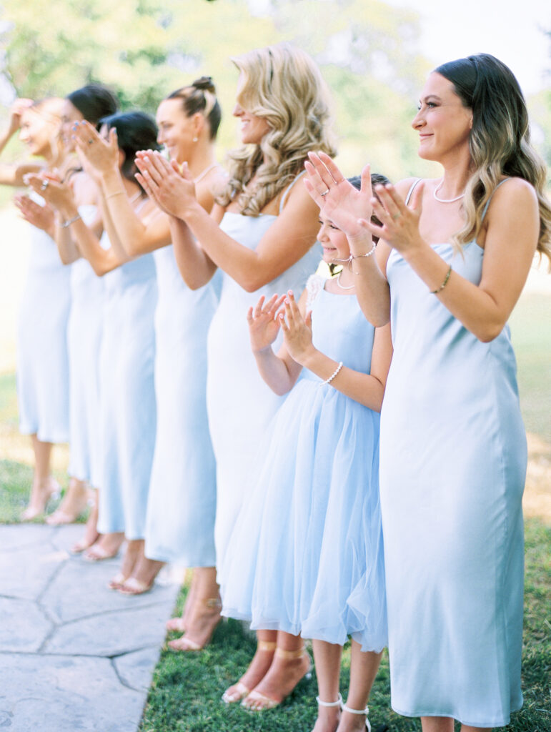 Bridesmaids in blue dresses smiling and clapping